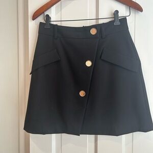 MAJE black a line mini skirt with gold button detail.